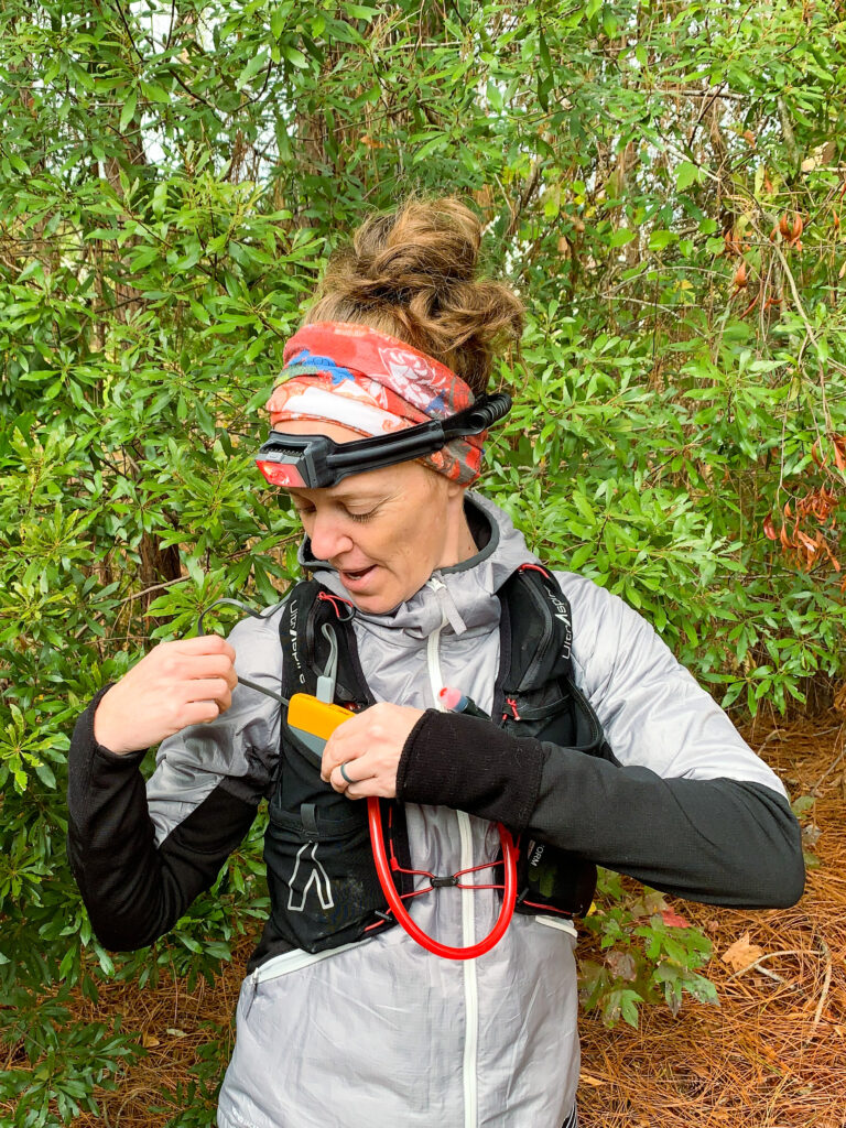 Heather Hart placing a power bank into a hydration pack demonstrating the charge-on-the-go feature of the BioLite HeadLamp 800 Pro
