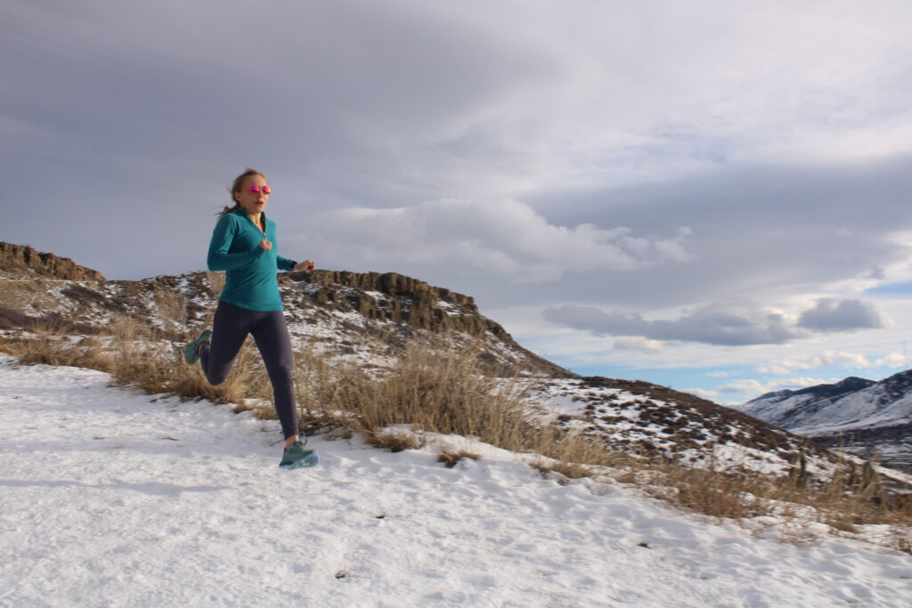 Female runner running downhill across the snow