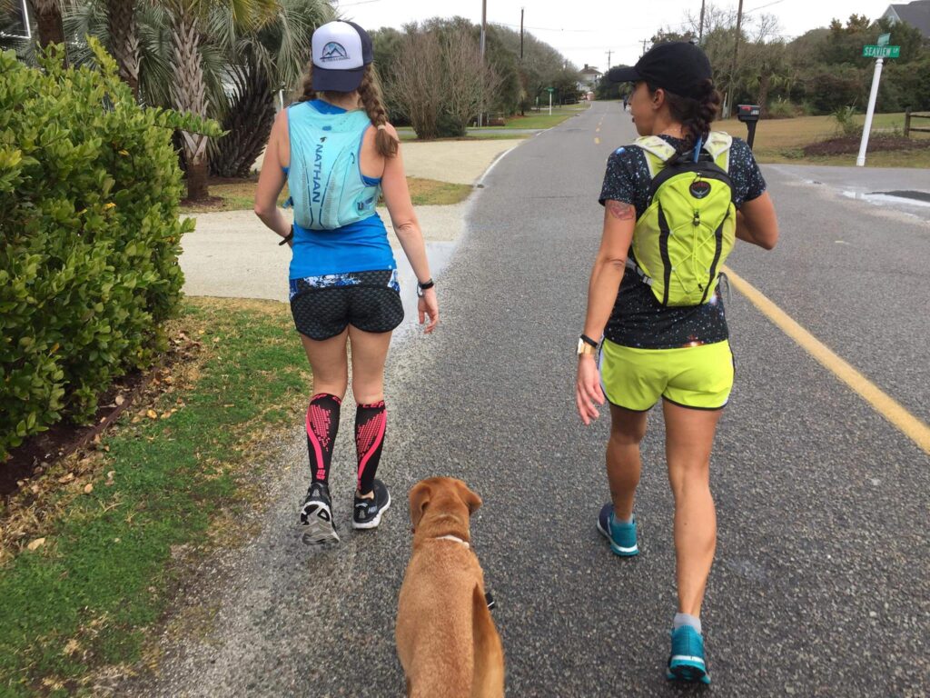 View of runners out for a training run on a rural paved road who are taking a walk break