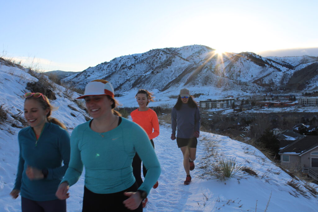 Jon Pham, Tanner Kaplan, Jackie Griggs, and Hannah Campbell winter trail running down North Table Mountain in Golden, Co. Photo by Lexi Miller. 