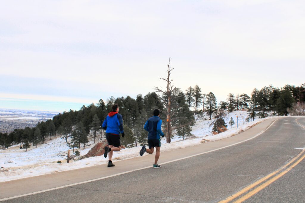 two athletes running up a long paved hill