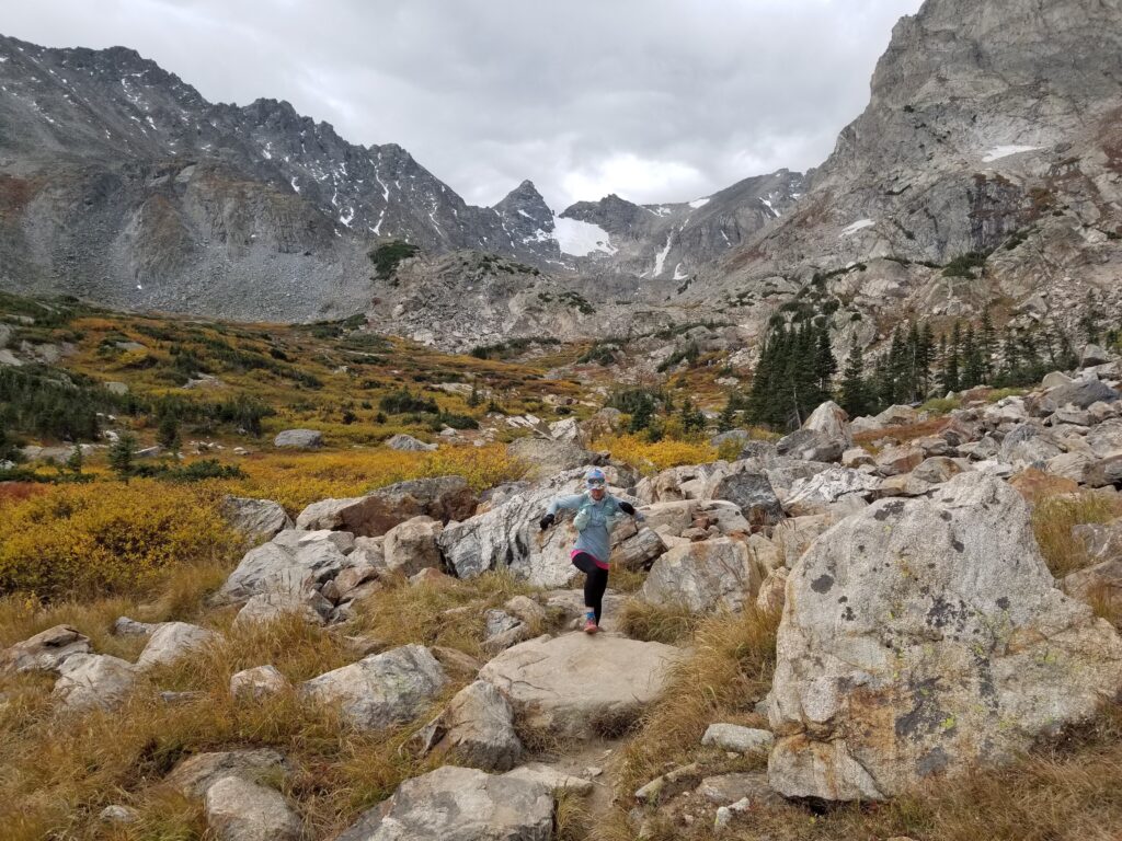 Coach Lexi Miller trail running through rocky terrain 