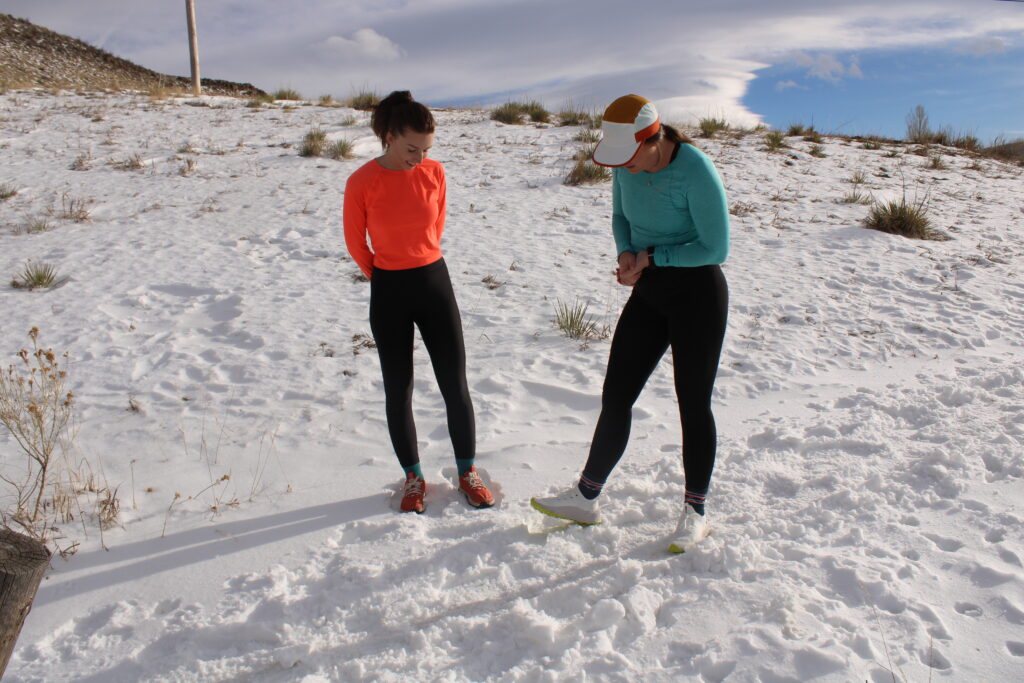 Trail runners looking at their running shoes while standing in the snow