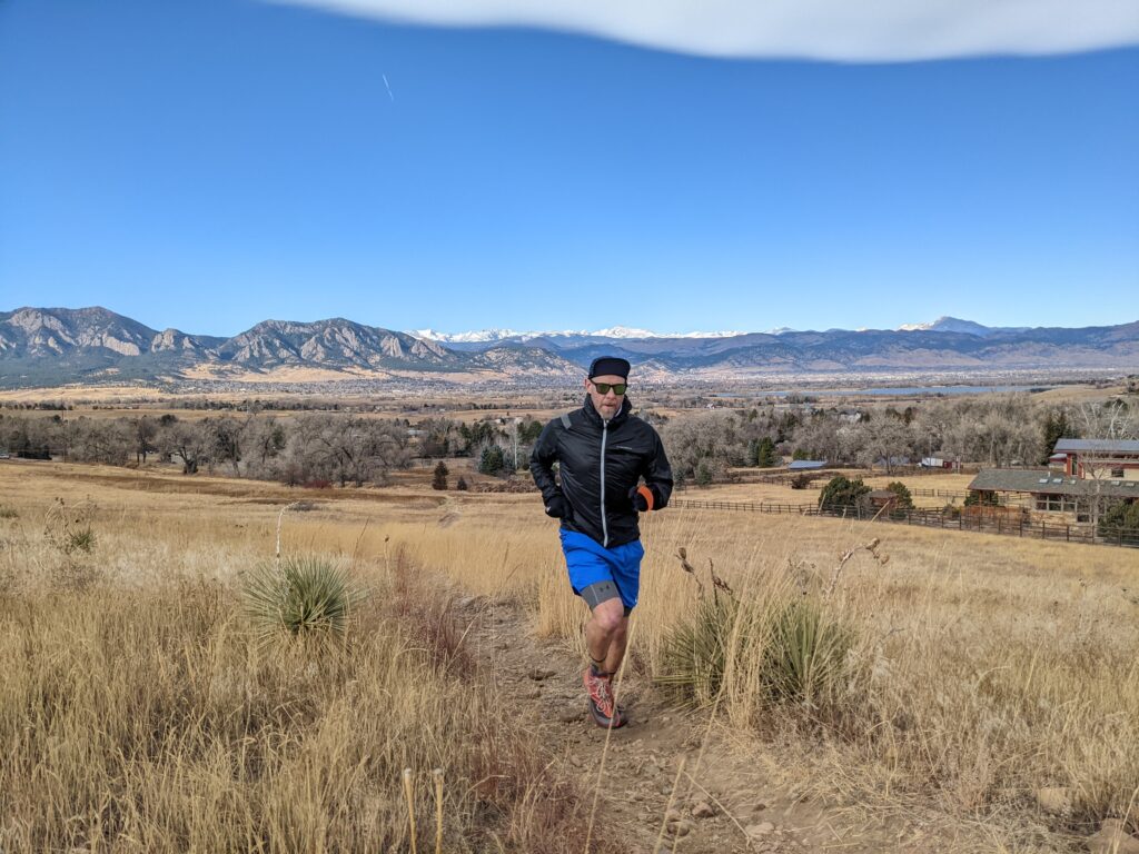 Trail runner running through a trail in a field with mountains in the background 