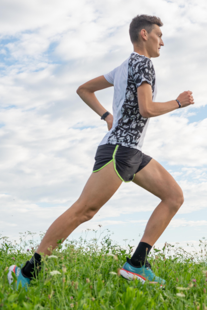 a runner demonstrates running strides drill form in a grassy field